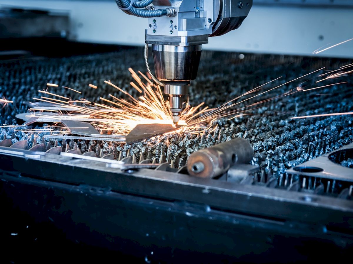 A CNC machine is cutting metal with sparks flying. The setup is in an industrial environment, focusing on precision engineering.